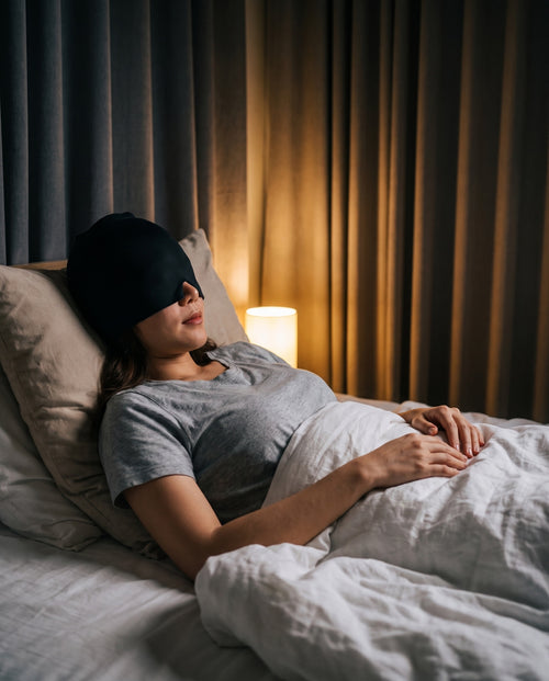 Woman resting in a dim bedroom wearing the Danevy Relief Cap